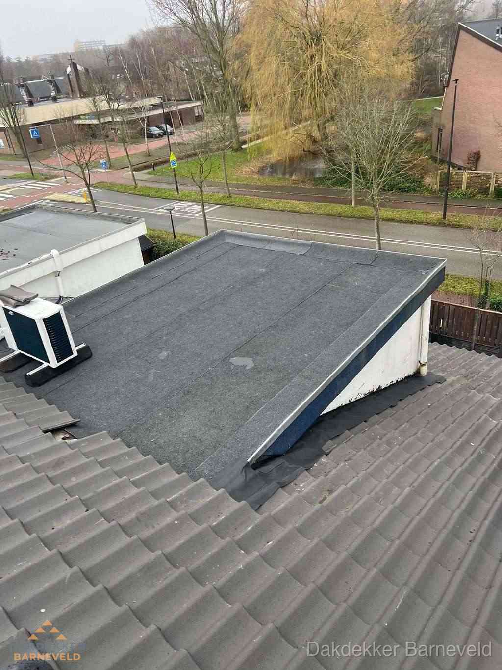 Plat dak met bitumen dakbedekking naast schuin pannendak in Barneveld